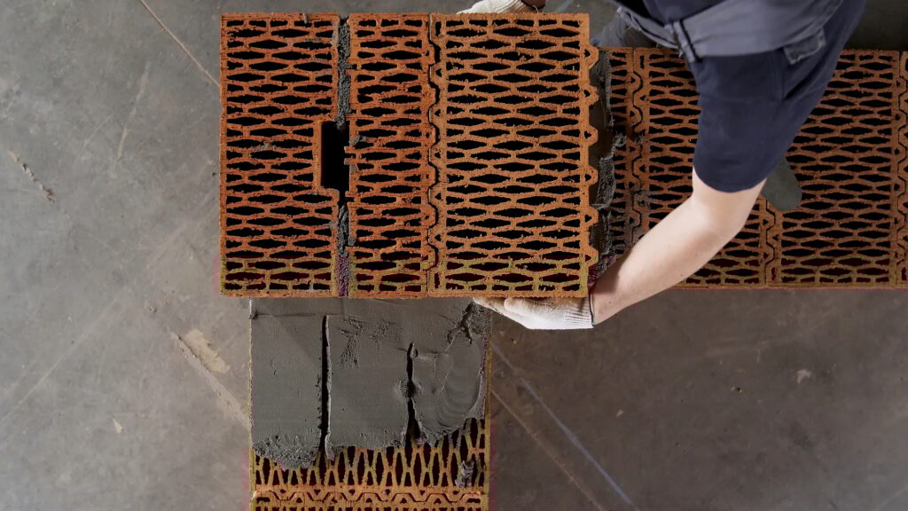 Top view of industrial bricklayer worker placing bricks on cement while building exterior walls